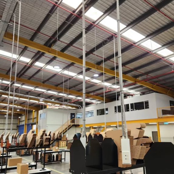 Power drops hanging from a warehouse roof down to packing benches