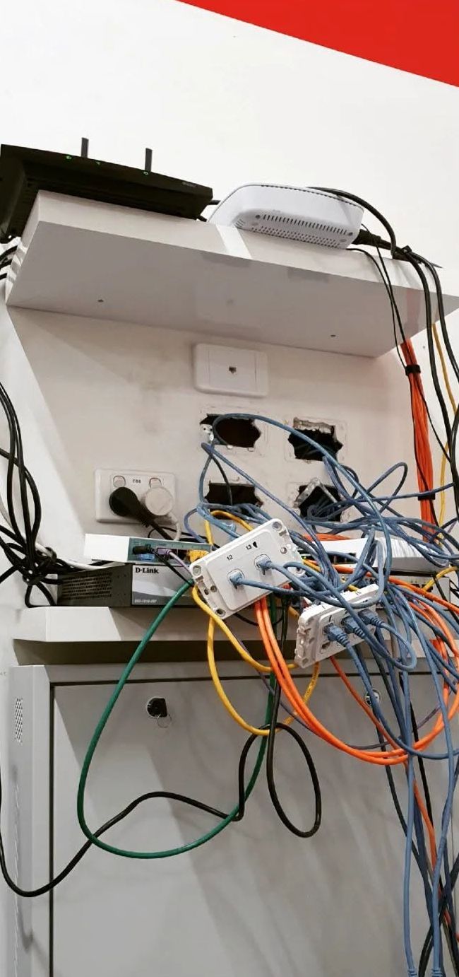 Before: network gear on an open shelf with tangled patch leads