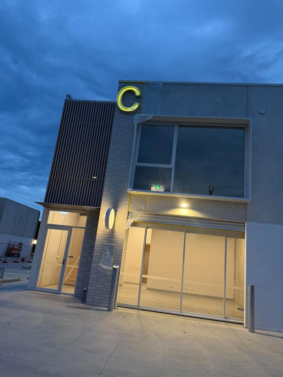 Commercial shopfront at dusk with an illuminated sign and entry lighting
